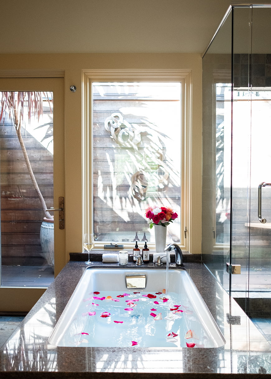 Luxury bathroom with rose petal bath and wine