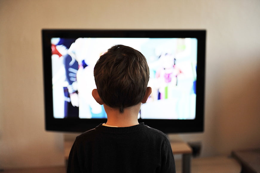 Young boy watching television from behind in a living room