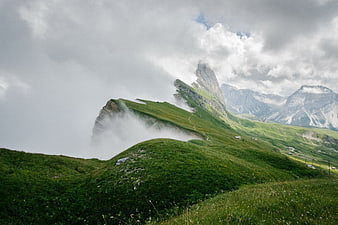 Misty green mountain ridge with dramatic clouds and distant peaks