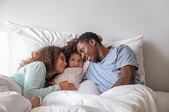 Happy African American Family Cuddling in Bed Together