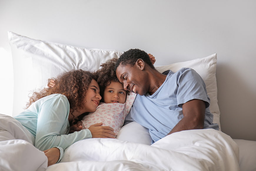 Happy African American Family Cuddling in Bed Together