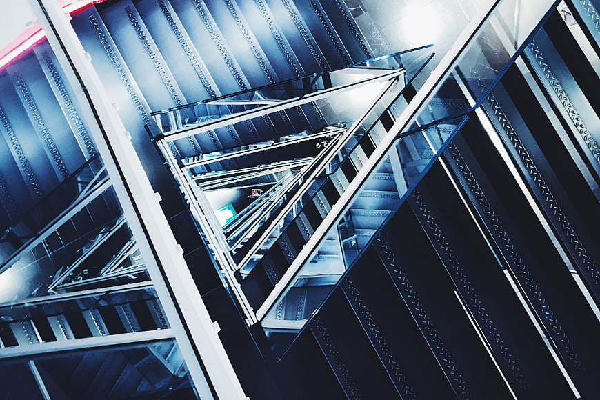 Modern metal staircase with glass railings and blue lighting