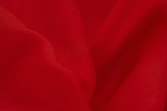 Close-up of red satin fabric with soft folds and texture