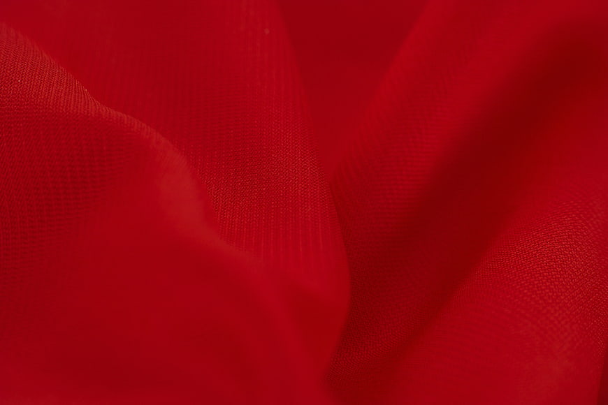 Close-up of red satin fabric with soft folds and texture