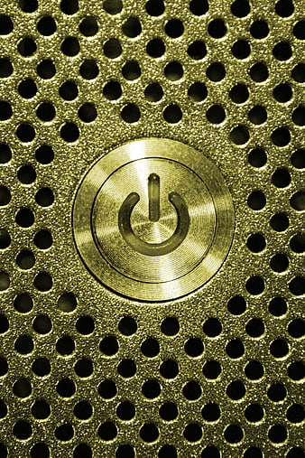 Close-up of gold power button on perforated metal texture