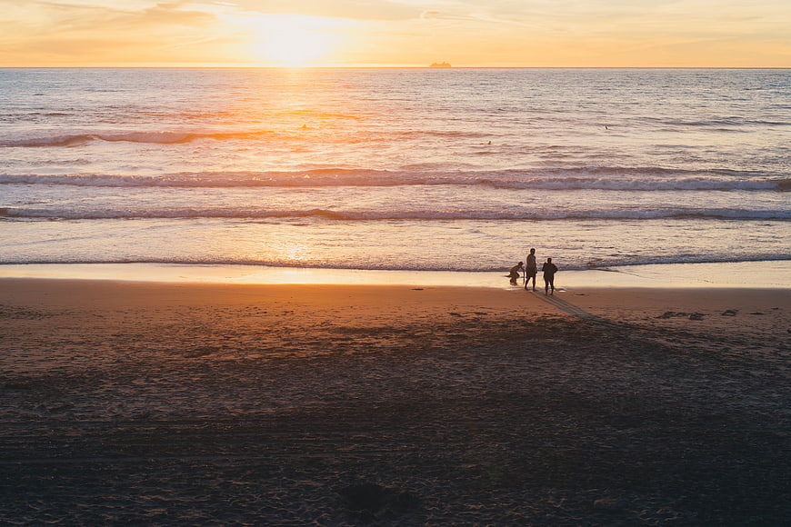 Silhouettes of people on a beach at golden sunset