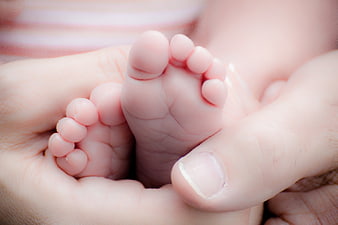 Close-up of newborn baby feet held in adult hands
