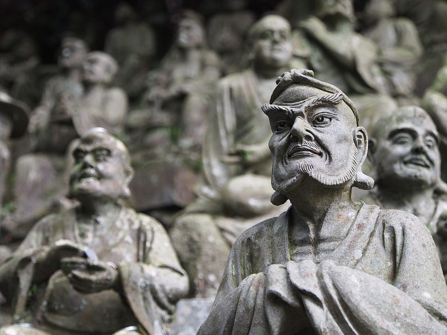 Close-up of weathered stone statues in a Japanese temple setting
