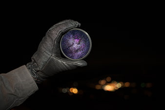Gloved Hand Holding Galaxy Lens Filter at Night