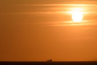 Silhouette of a ship on the ocean during a golden sunset