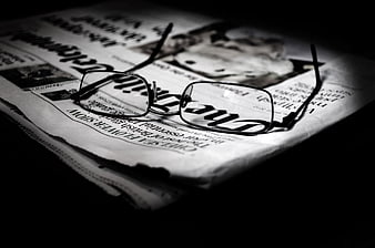 Black and white reading glasses on newspaper