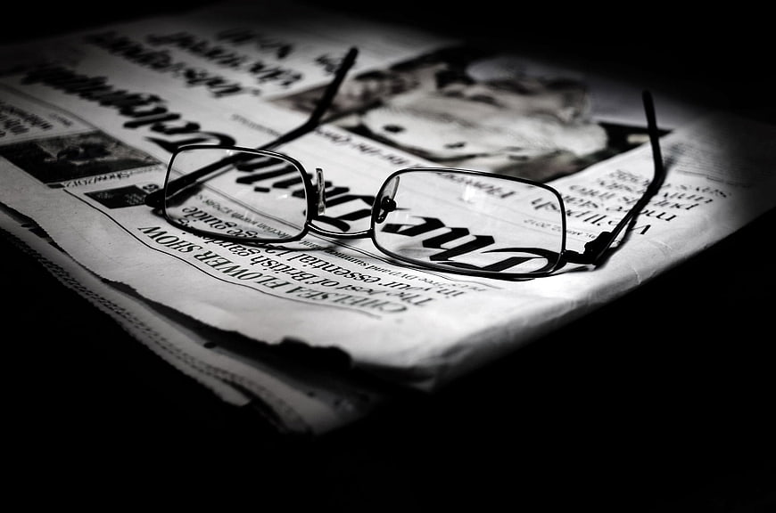 Black and white reading glasses on newspaper