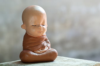 Small clay monk statue meditating in peaceful pose