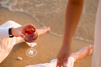 Couple Enjoying Red Wine on Sandy Beach at Sunset