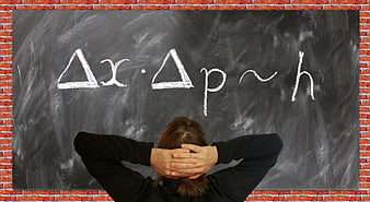Student studying Heisenberg uncertainty principle on chalkboard