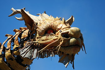 Detailed wooden dragon head sculpture against blue sky