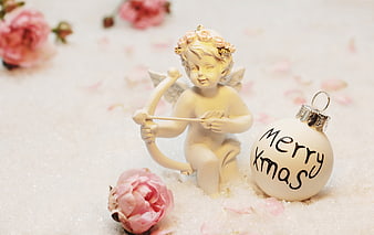 Cupid figurine with bow and arrow next to Merry Xmas ornament