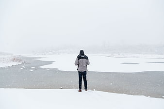 Man Standing Alone on Frozen River in Snowstorm