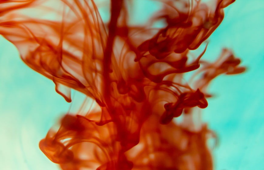 Abstract Red Ink Swirling in Turquoise Water