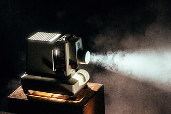 Vintage film projector emitting smoke beam in dark studio