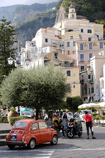Vintage red Fiat 500 parked in Italian coastal town square