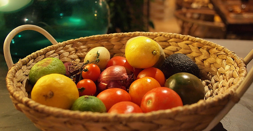 Woven basket of fresh lemons, tomatoes, and vegetables