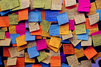 Colorful sticky notes with handwritten messages on dark background