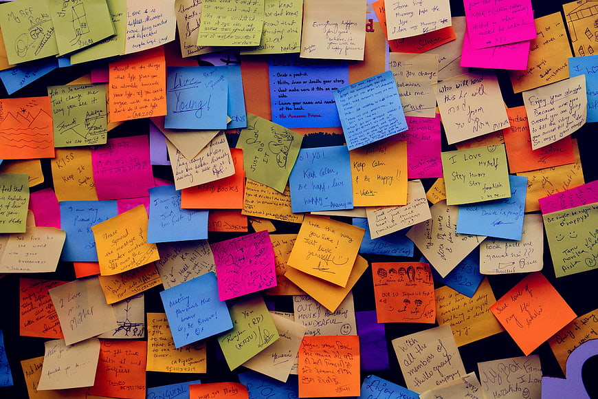 Colorful sticky notes with handwritten messages on dark background
