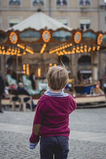 Child Watching Carousel with Bokeh Lights