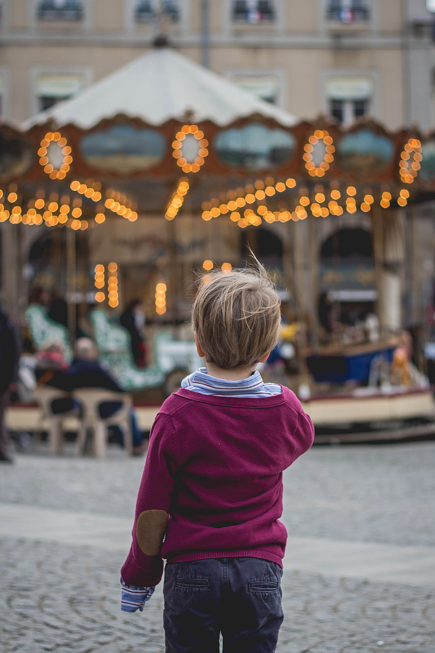 Child Watching Carousel with Bokeh Lights