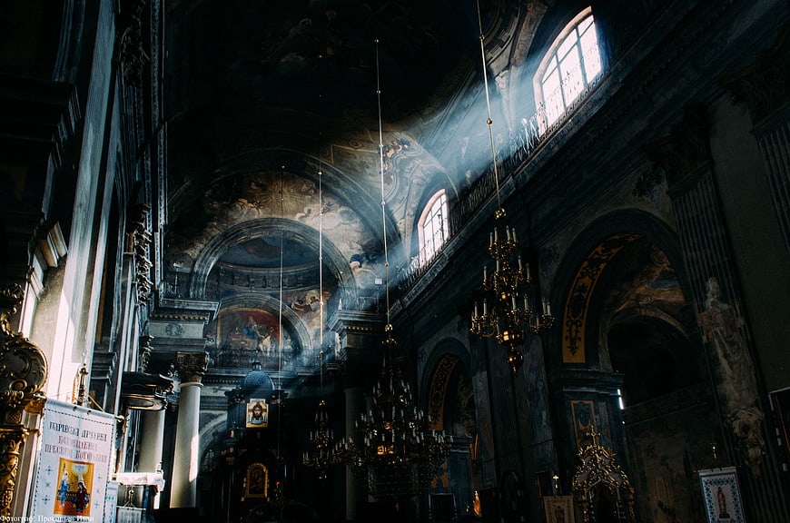Sunbeams streaming through high windows in an ornate Orthodox church interior