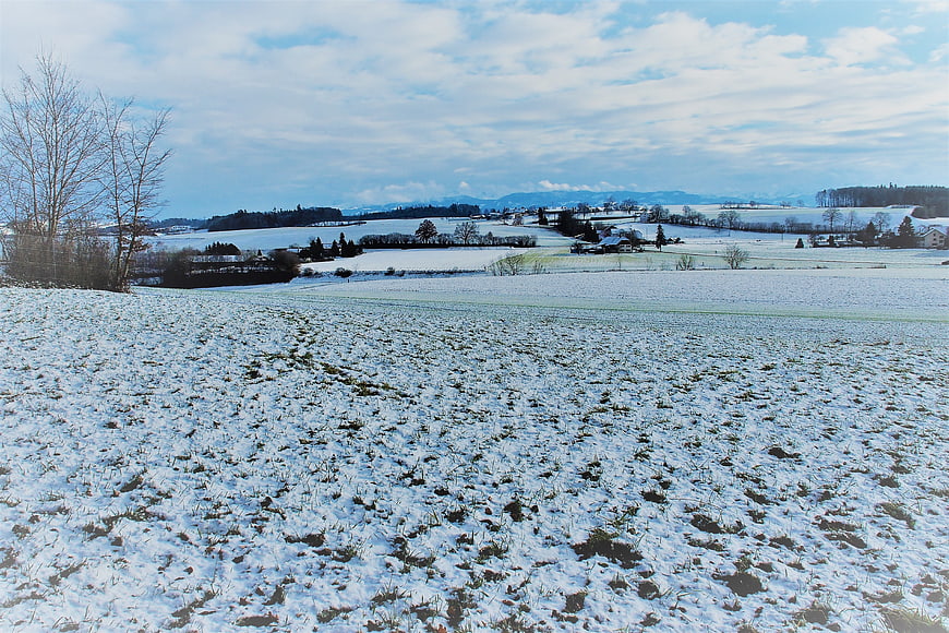 Snowy Winter Landscape with Rolling Hills and Distant Mountains