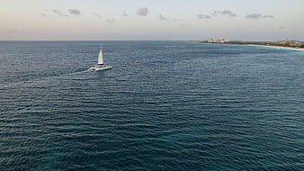 Aerial view of sailboat on blue ocean near coastline