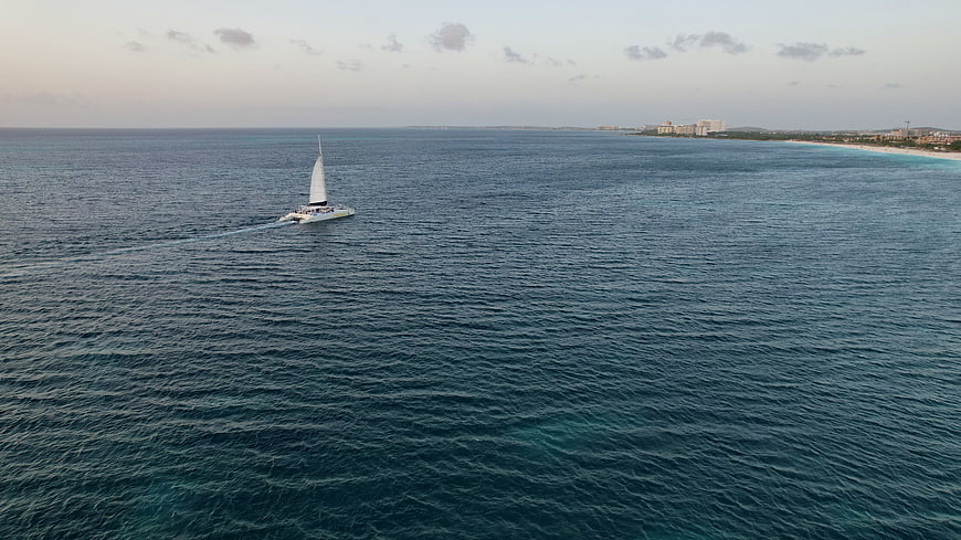 Aerial view of sailboat on blue ocean near coastline