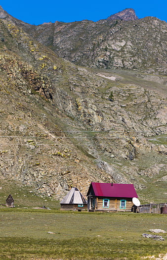 Rustic wooden cabin with red roof in mountain landscape