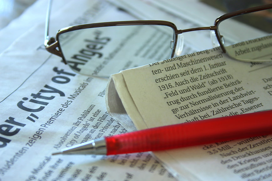 Close-up of red pen and glasses on German newspaper