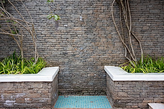 Outdoor stone shower with blue mosaic tiles and green plants