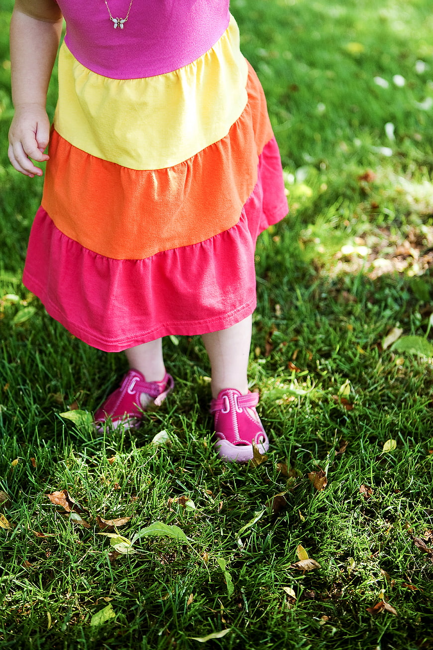 Toddler Girl in Colorful Tiered Dress Standing on Grass
