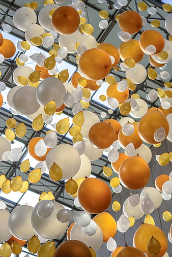 Yellow, Orange, and White Balloons Hanging from Glass Ceiling