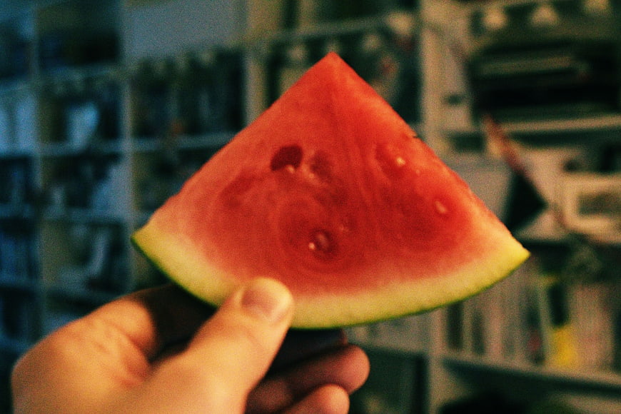 Hand holding slice of red watermelon indoors