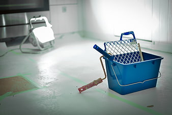 Blue paint bucket and roller on taped floor during renovation