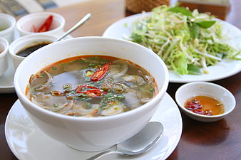 Bowl of Vietnamese Bun Bo Hue Soup with Fresh Herbs