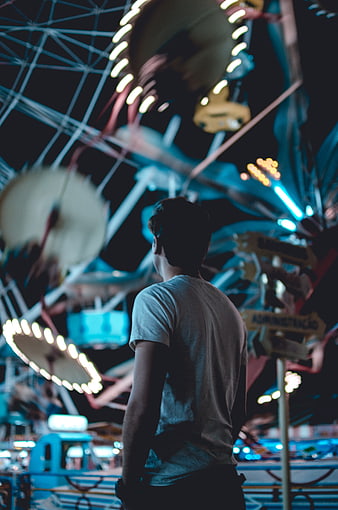 Man watching amusement park ride at night
