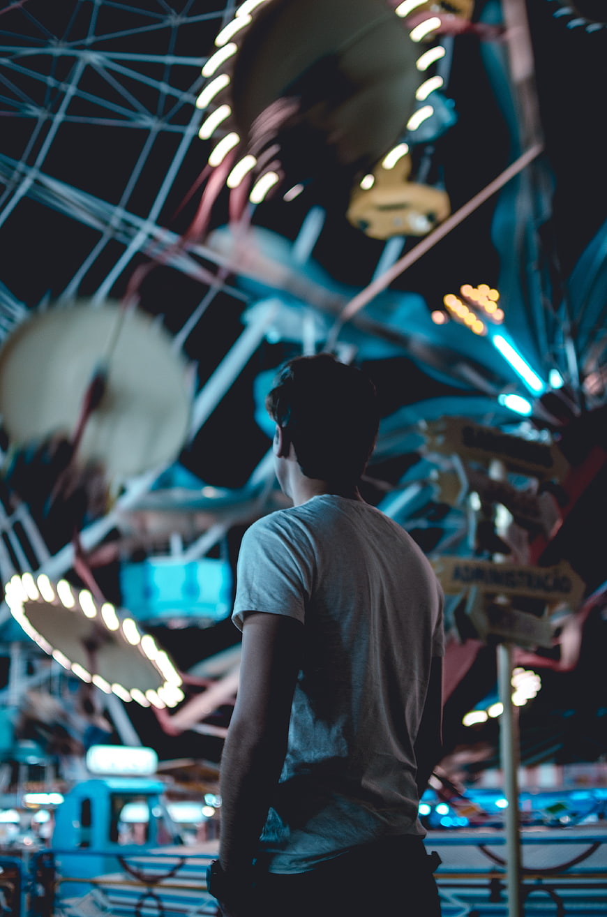 Man watching amusement park ride at night