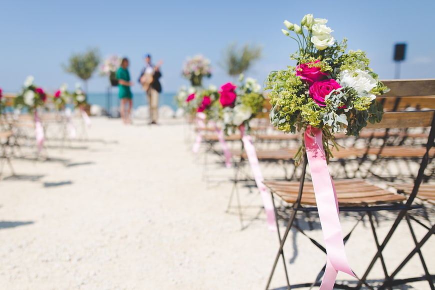 Beach Wedding Ceremony Setup with Floral Bouquets on Chairs