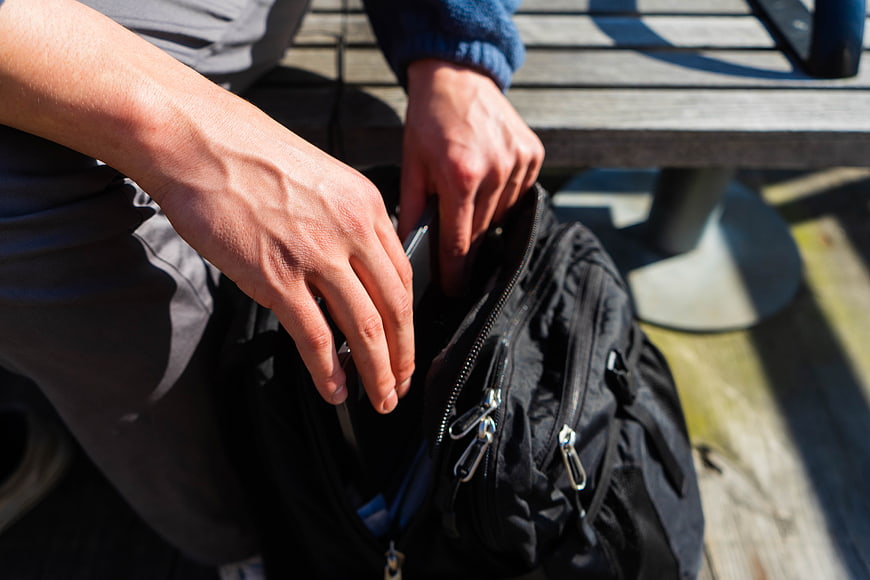 Close-up of hands packing a black backpack outdoors