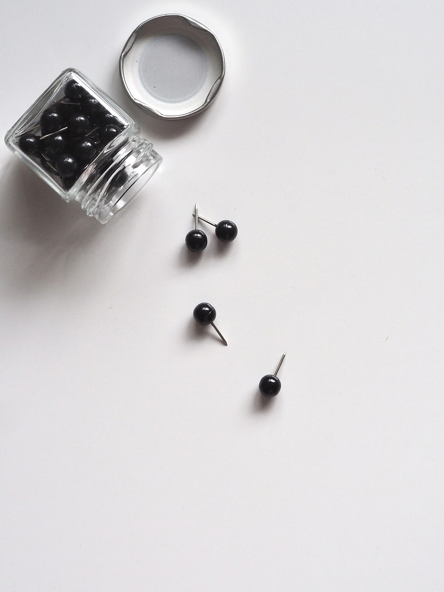 Minimalist Black Pins in Glass Jar on White Background