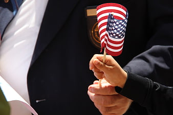 Child Holding Small American Flag in Front of Veteran