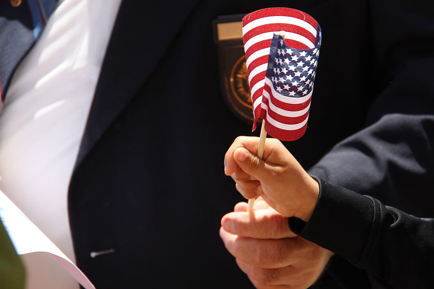 Child Holding Small American Flag in Front of Veteran