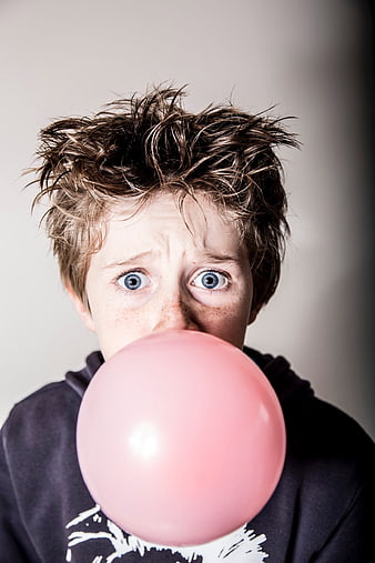 Boy blowing large pink bubble gum bubble